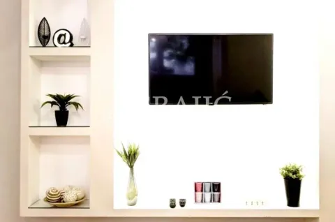 Living room with built-in shelves and a wall-mounted TV. - image 4