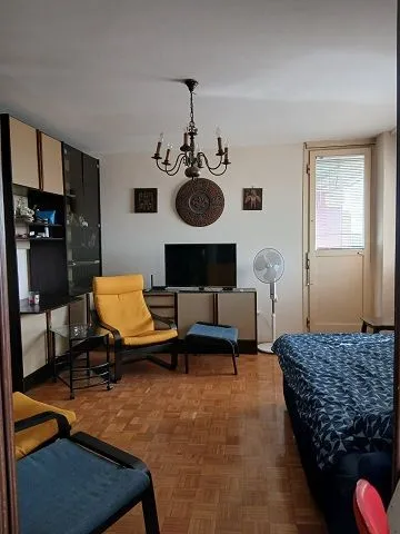 Living room with seating furniture, television, and parquet flooring.