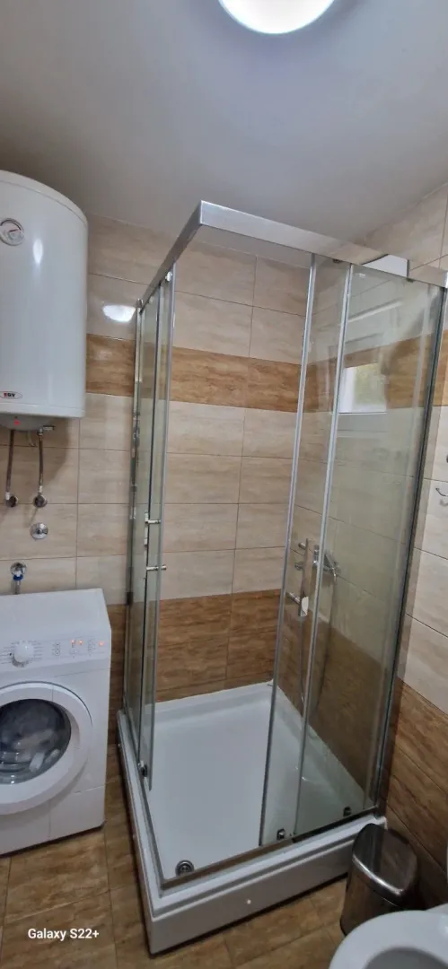 Smaller bathroom with a shower cabin, water heater, and washing machine.