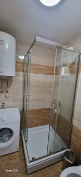 Smaller bathroom with a shower cabin, water heater, and washing machine. - image 8