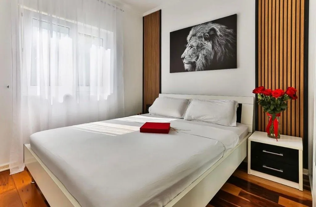 Furnished bedroom with a double bed, nightstand, and a lion painting on the wall.
