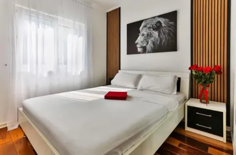 Furnished bedroom with a double bed, nightstand, and a lion painting on the wall. - image 8