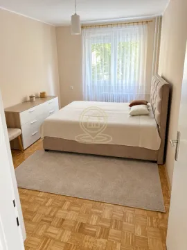 Nameštena spavaća soba sa bračnim krevetom, komodom i prozorom. - image 4
