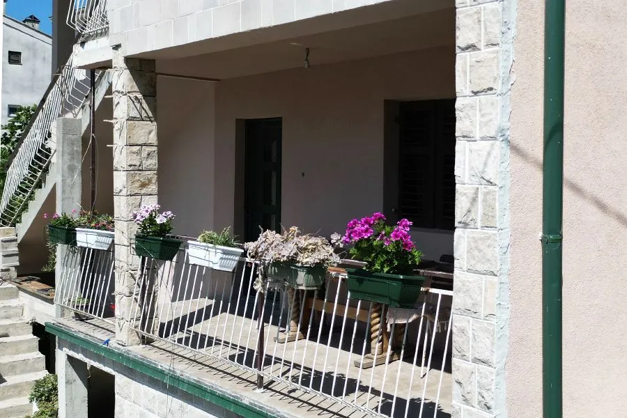 Covered terrace with flowers and a railing on the house.