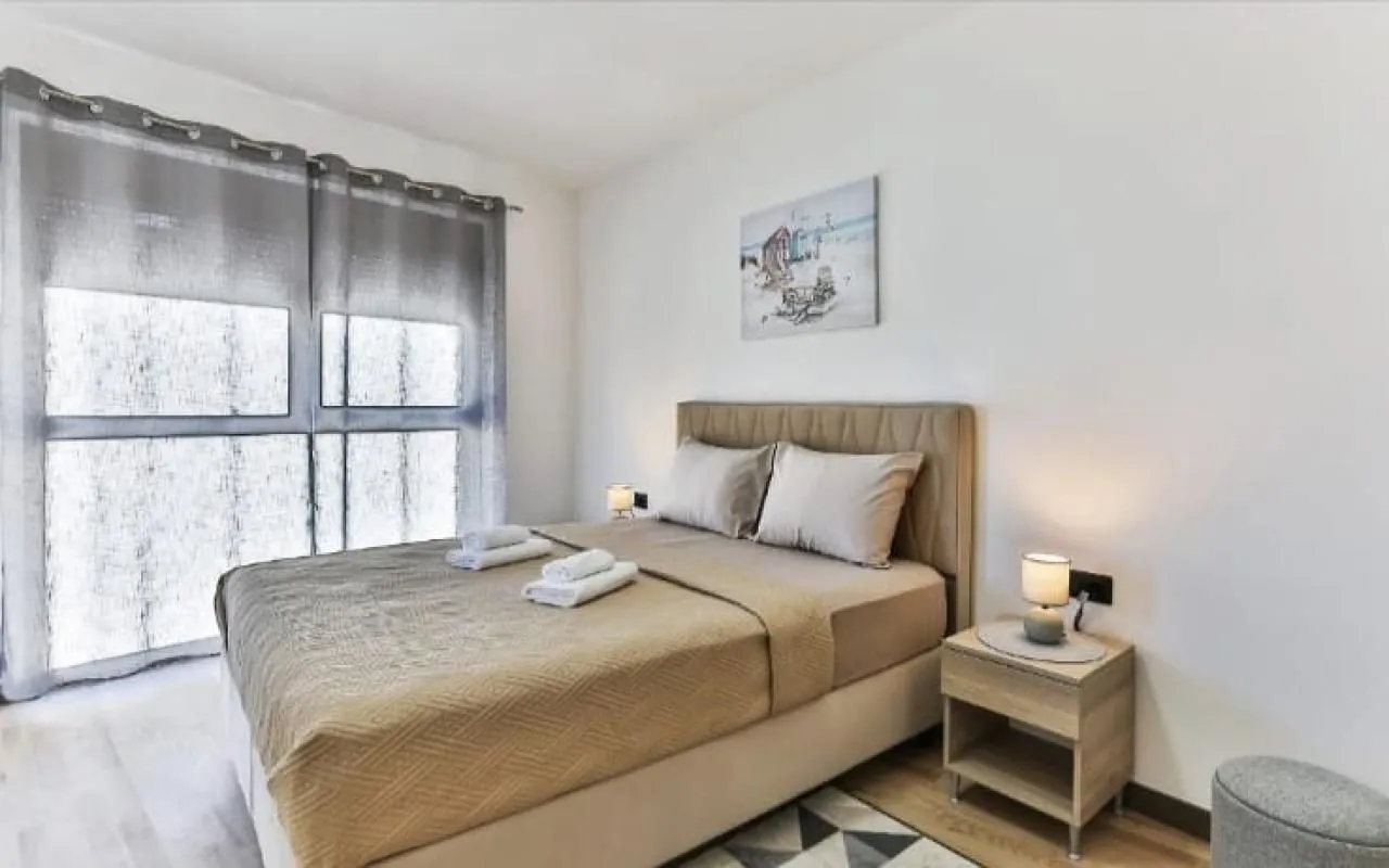 Furnished bedroom with a double bed, bedside tables, and a curtained window.