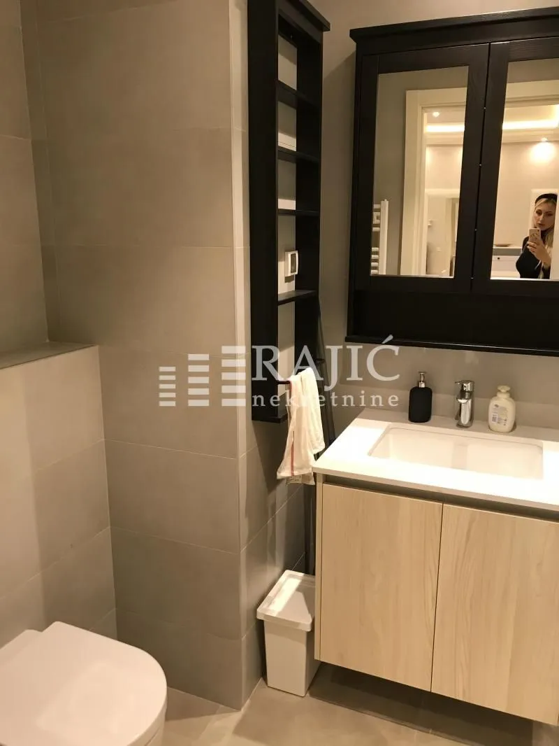Modern bathroom with a sink, mirror, and toilet.