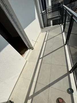 Prazan prostrani balkon sa keramičkim pločicama i ogradom od tamnog metala. - image 5