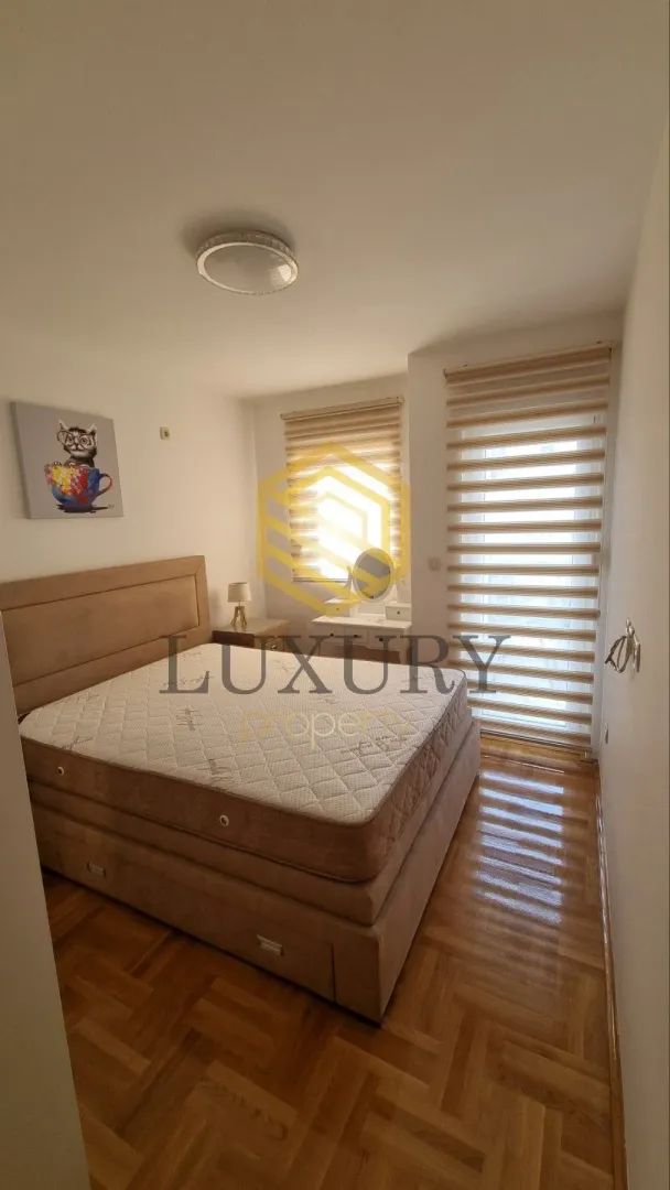 Bright bedroom with a double bed and parquet flooring.