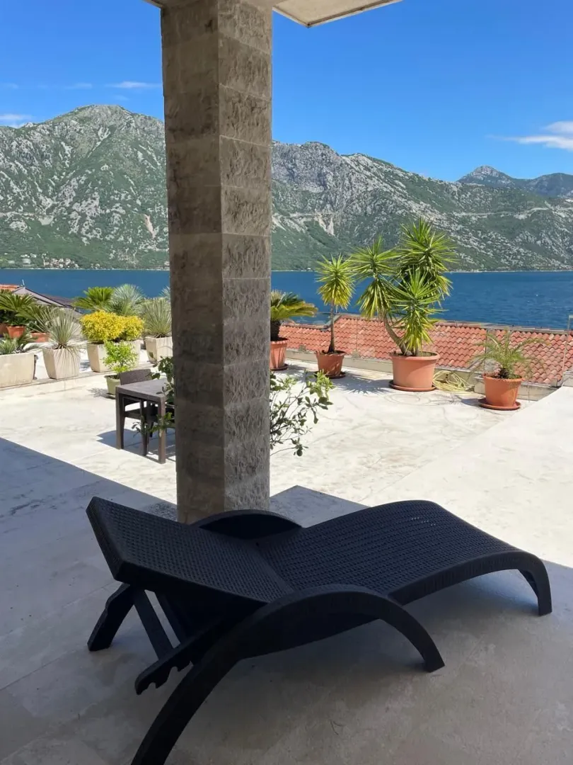 Prostrana terasa sa ležaljkom i pogledom na more i planine.
