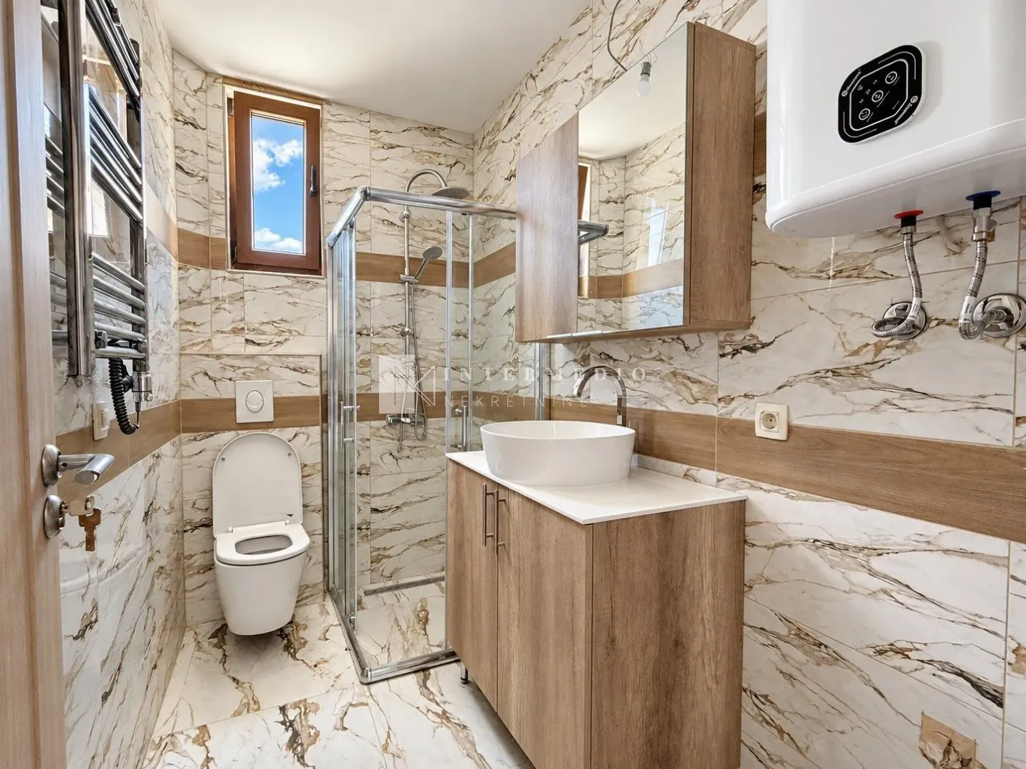 Moderne kupatilo sa tuš kabinom, umivaonikom i ugradnom sanitarijom.