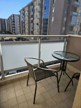 Manji namješteni balkon sa stolom i stolicama i pogledom na zgrade. - image 9