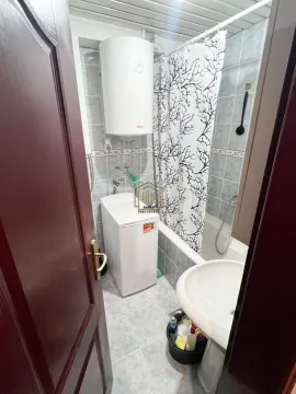 Small bathroom with a bathtub, washbasin, water heater, and washing machine. - image 6