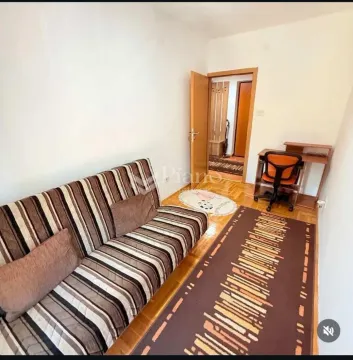 Small living room with a sofa, rug, and a desk. - image 6