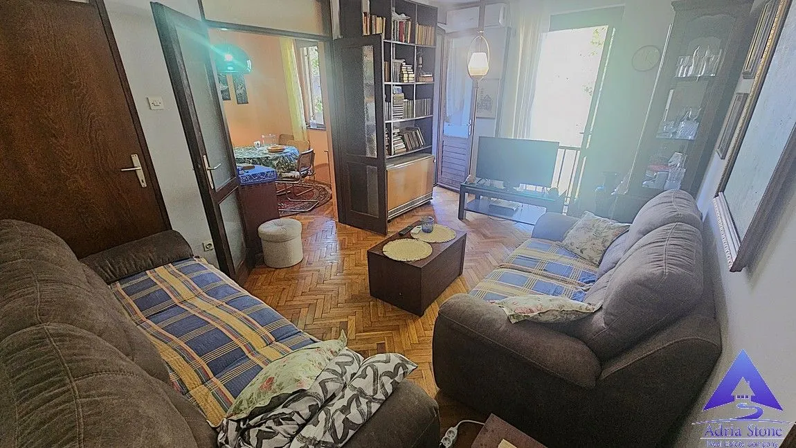 Namještena dnevna soba sa sofama, stočićem i pogledom na susjednu prostoriju.