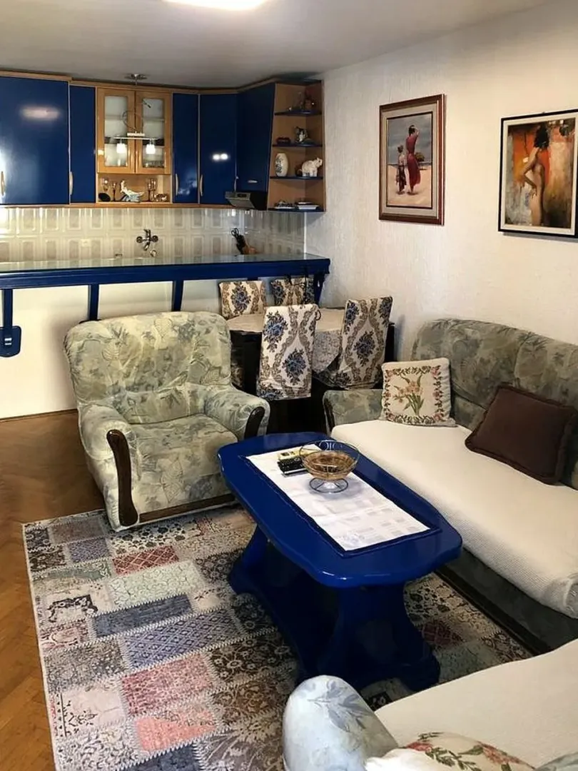 Living room with a sofa set and a kitchen area in the background.