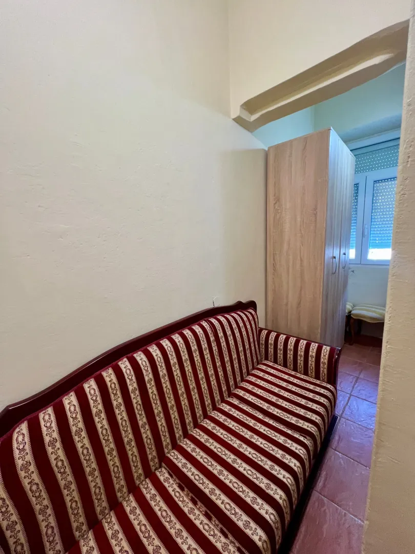 Living room with a sofa and a passageway to a room with a wardrobe.
