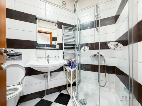 Kompaktno kupatilo sa tuš kabinom, umivaonikom, toaletom i crno-bijelim pločicama. - image 9