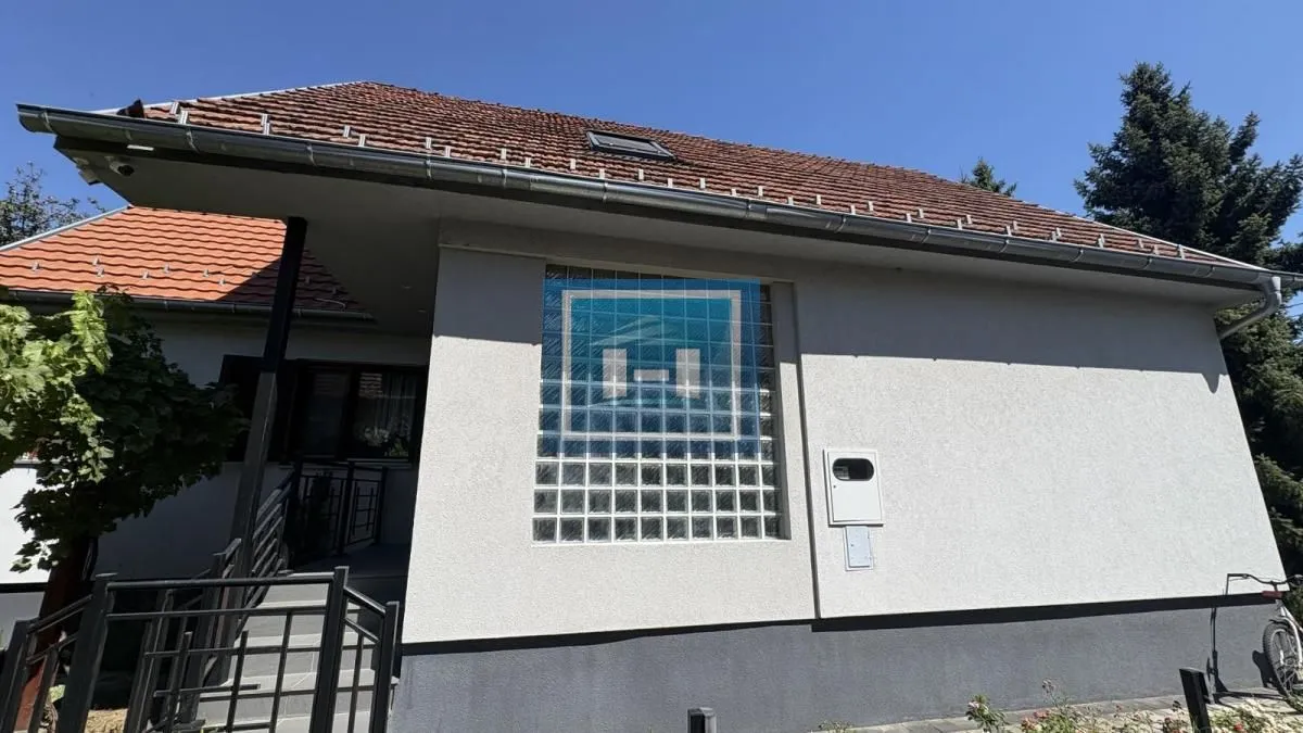 Pogled na spoljašnjost kuće sa krovom i staklenim blokovima na zidu.