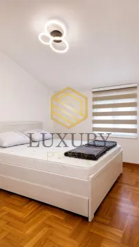 Spavaća soba sa bračnim krevetom, parketom na podu i modernim lusterom. - image 6