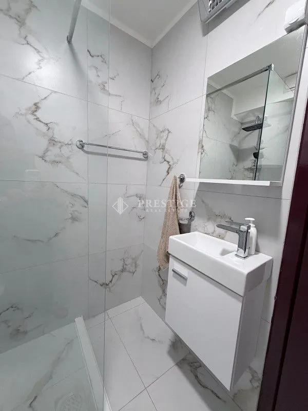 Modern bathroom with a washbasin and walk-in shower finished in marble-effect tiles.