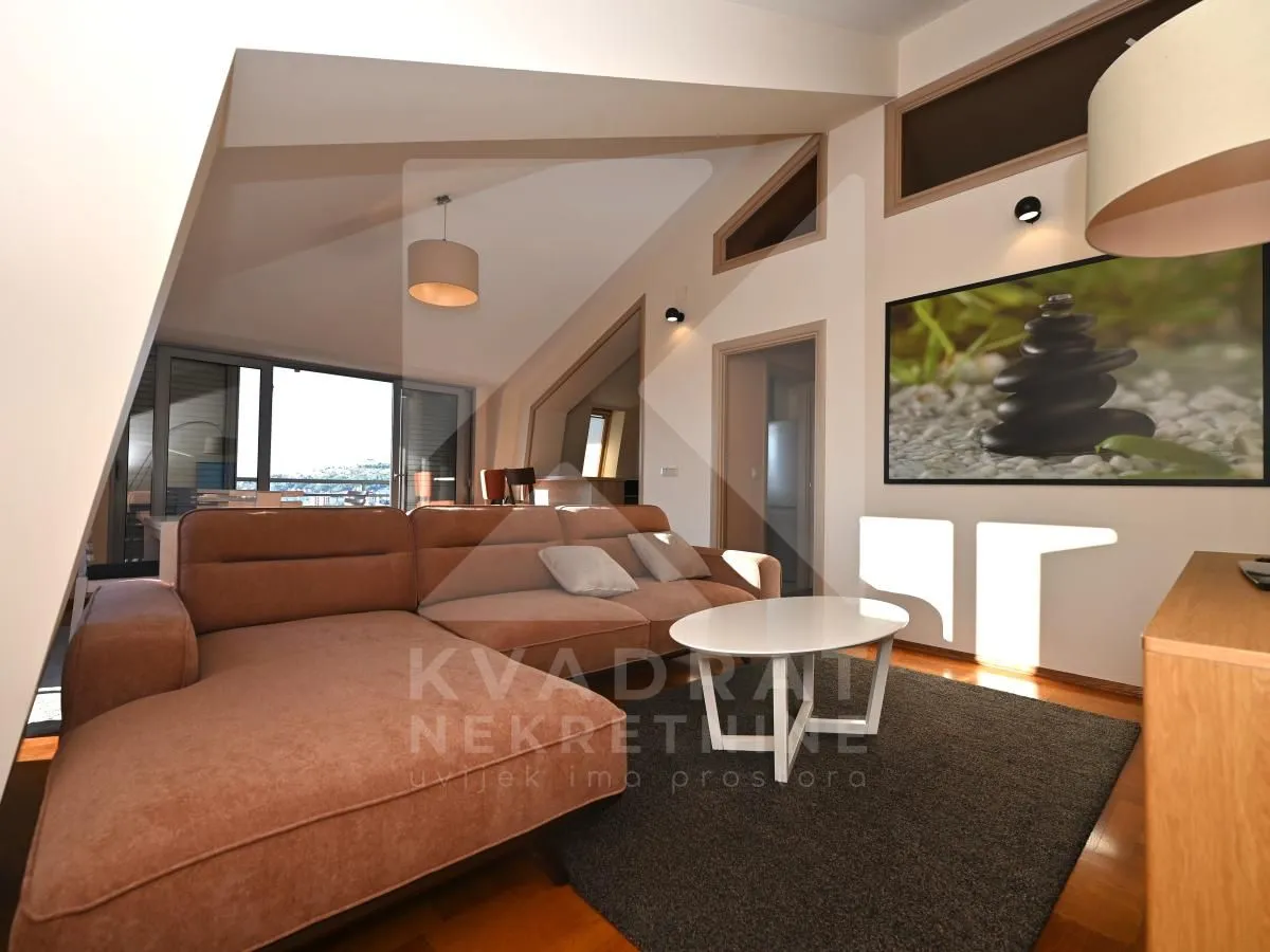 Living room with a sectional sofa, coffee table and sloping ceiling.