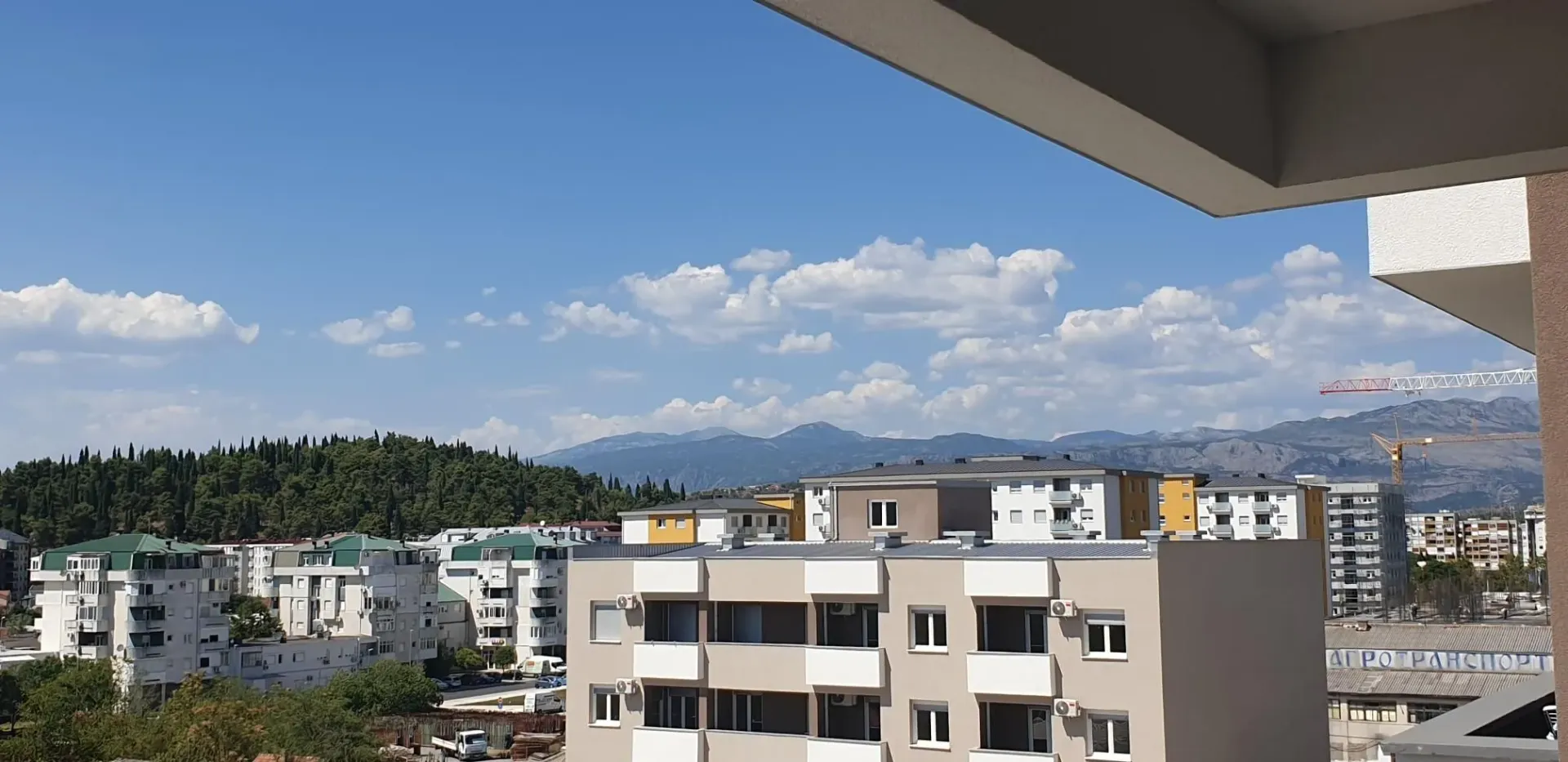 Pogled sa terase na gradske zgrade i brda u daljini.
