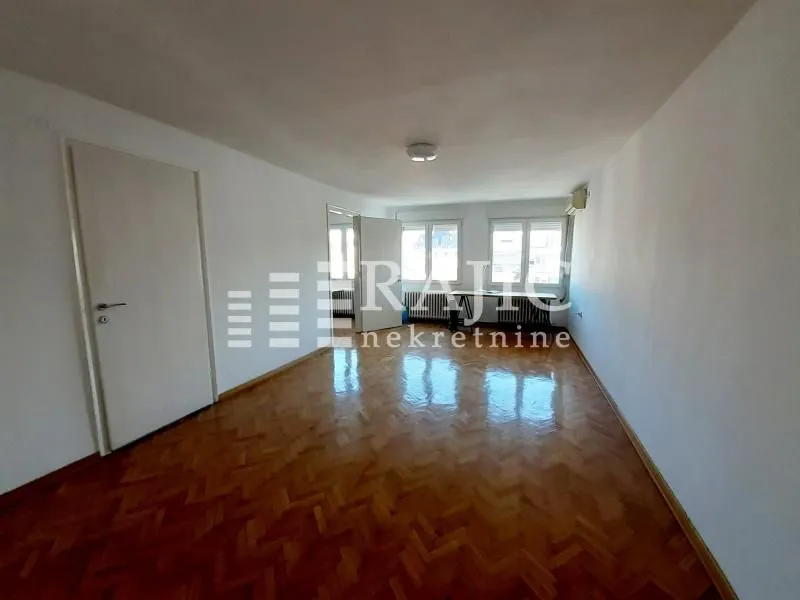 Empty room with parquet flooring and white walls.