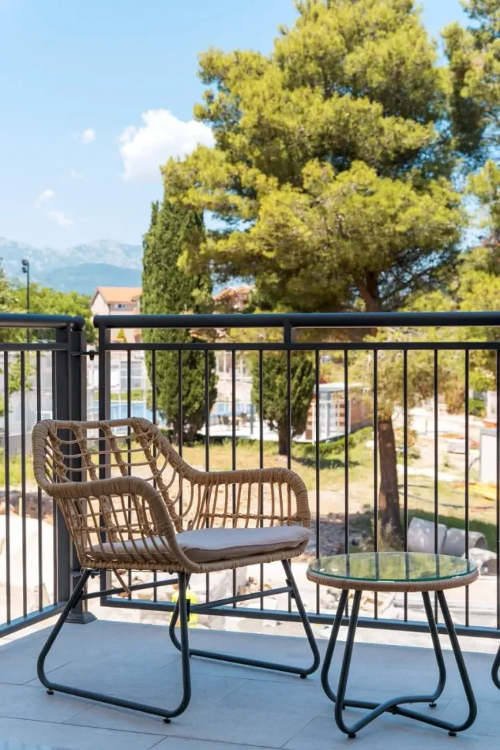 Namješten balkon sa foteljom i stolićem i pogledom na zelenilo.