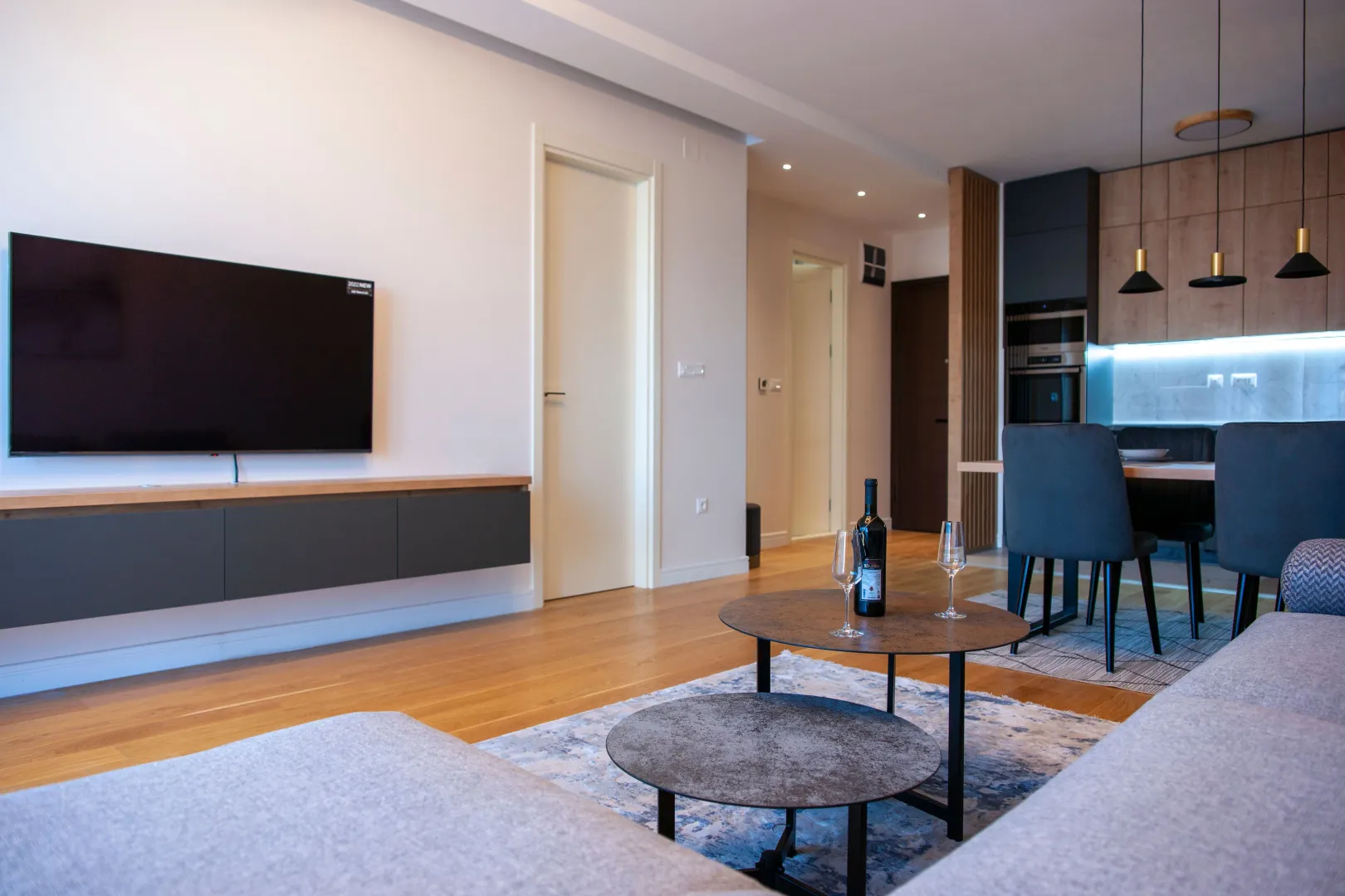 Living room with sofa, TV, and view of the kitchen and dining area.