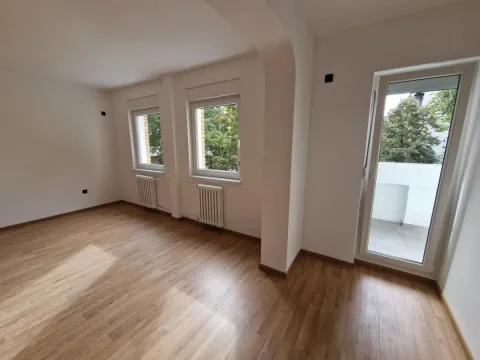 Prazna soba sa drvenim podom, belim zidovima i izlazom na terasu. - image 17