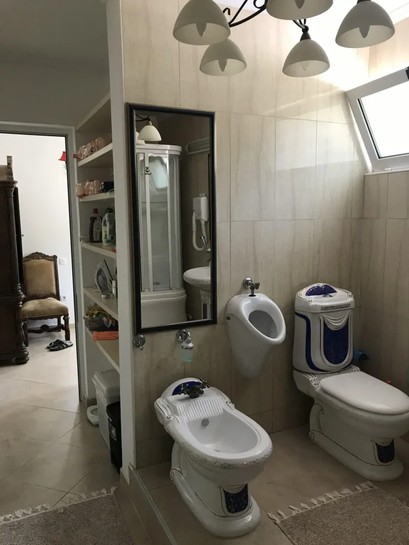 Kupatilo sa toaletom, bideom, pisoarom i policama za odlaganje.
