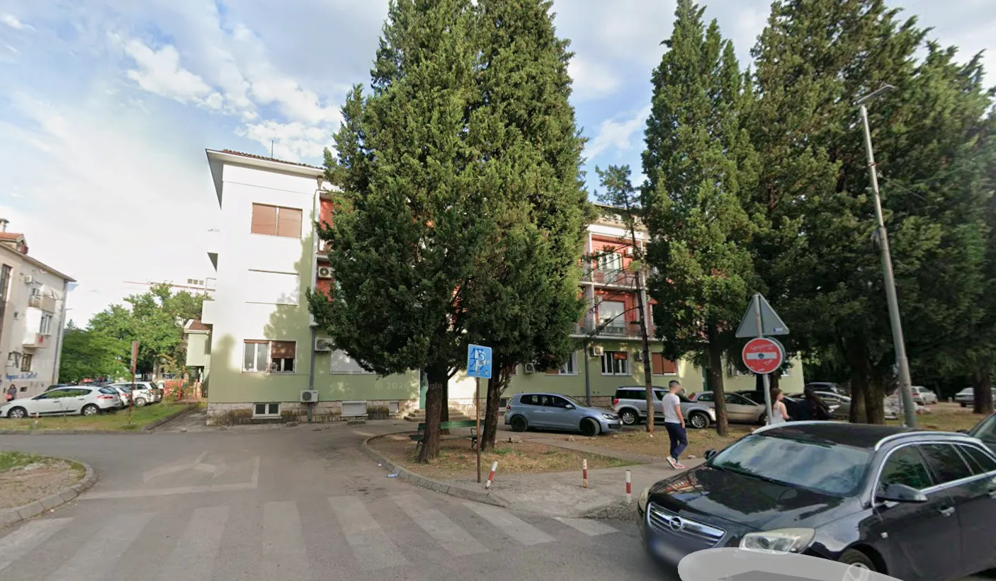 Pogled na spoljašnjost zgrade i okolno zelenilo.