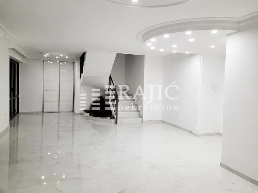 Spacious bright living room with marble flooring and a staircase.