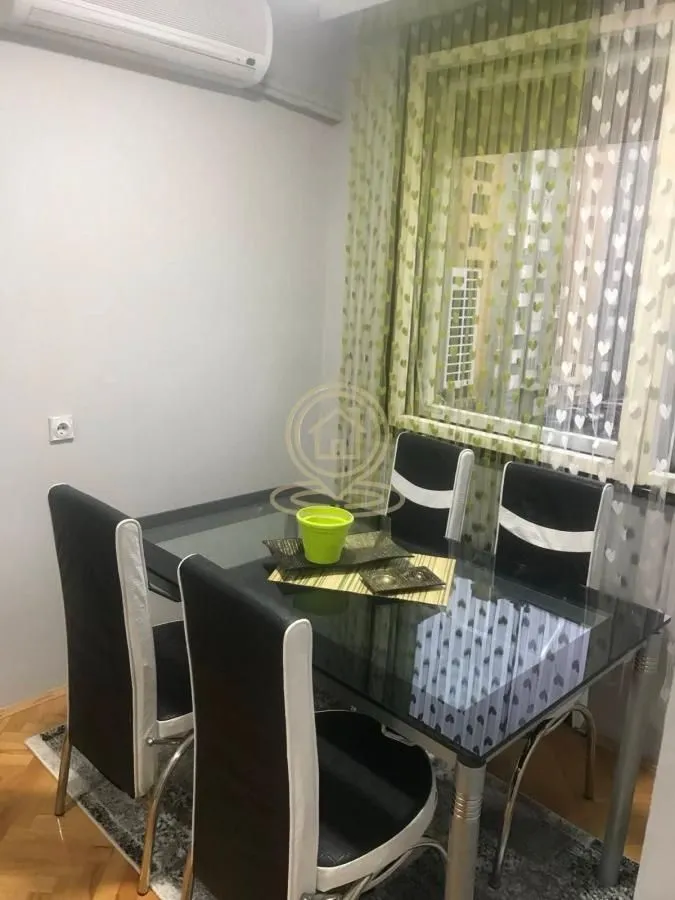 Trpezarijski sto sa crnim stolicama u svetloj prostoriji.