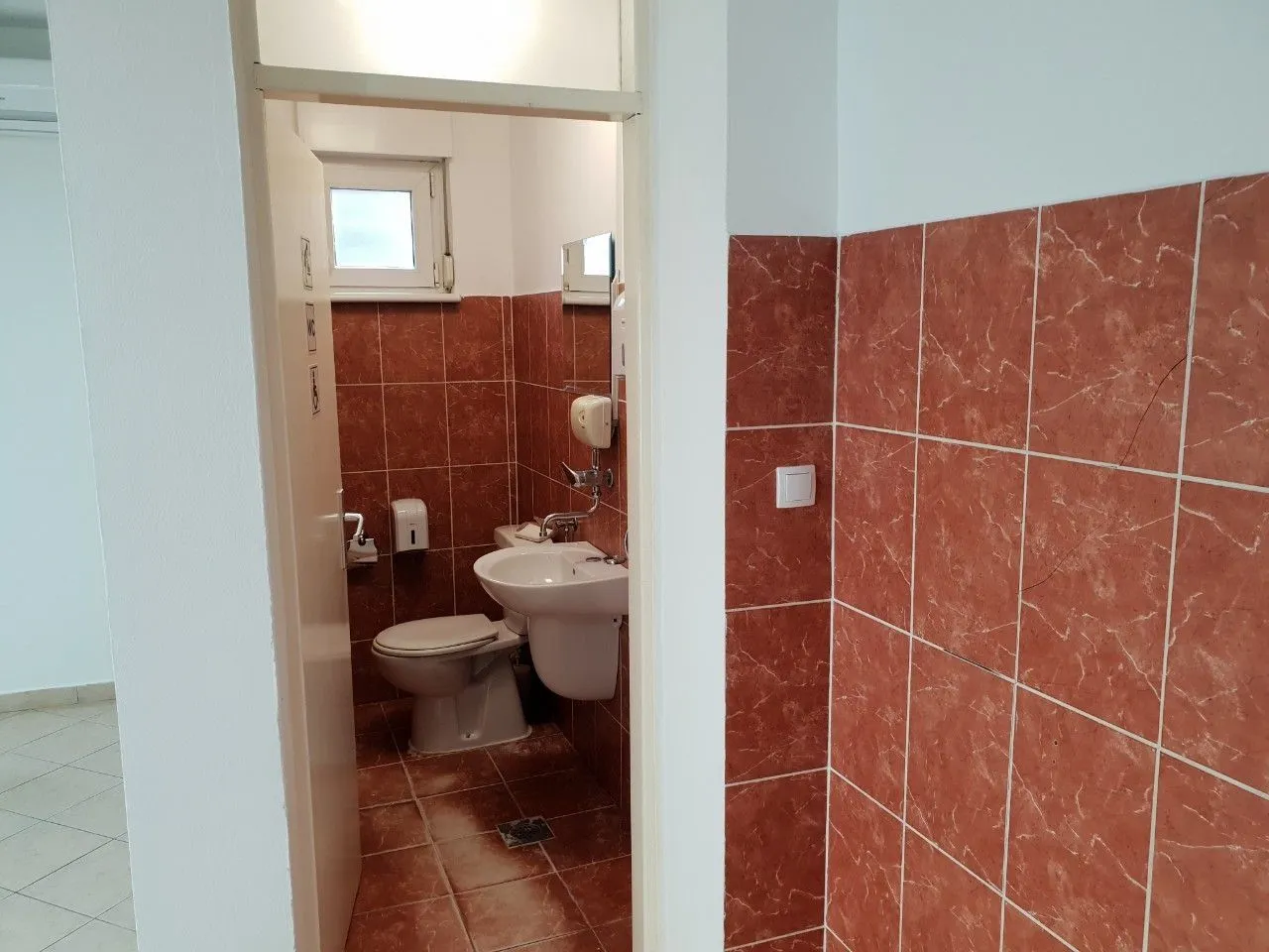 Small bathroom with brown tiles, a sink, and a toilet.