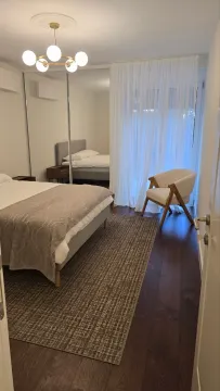 Modern bedroom with a double bed, mirrored wardrobe, and an armchair. - image 9