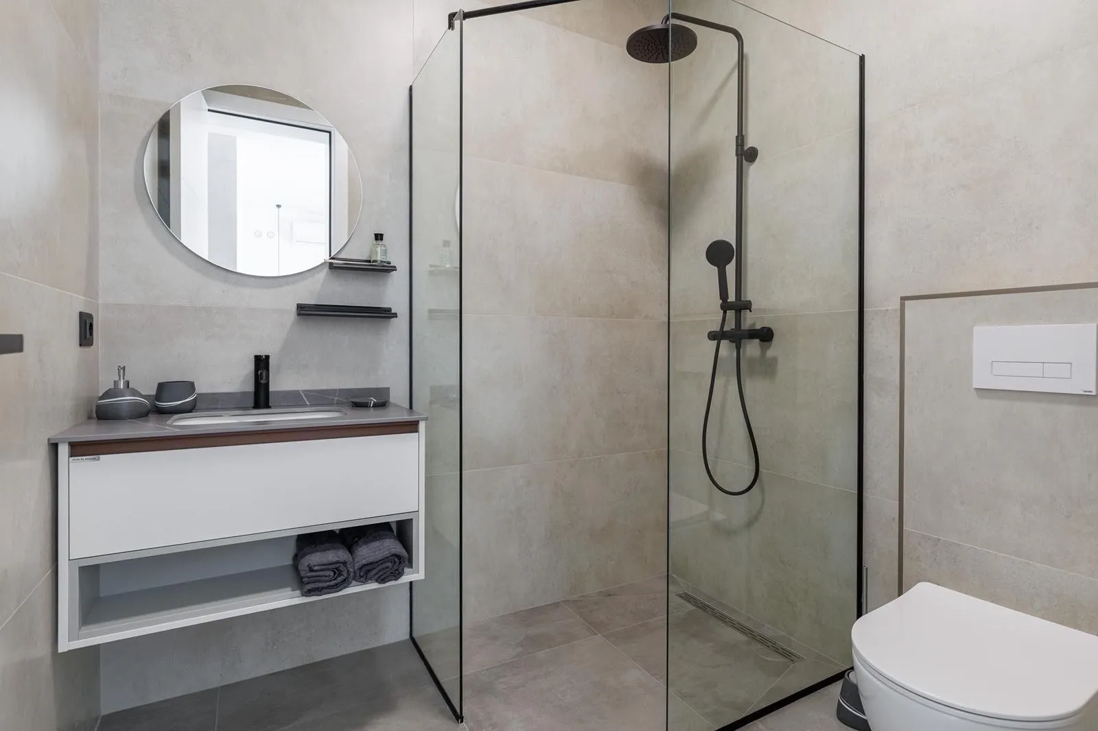 Modern bathroom with a shower cabin, washbasin, and toilet.