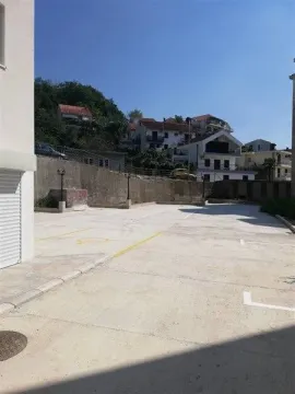 Popločani parking prostor ispred zgrade sa pogledom na okolne kuće. - image 3