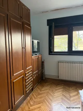 Spavaća soba sa drvenim ormanima, TV-om i parketom. - image 11