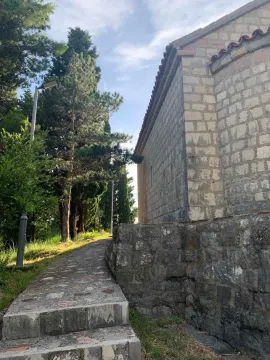 Eksterijer kamene kuće sa stazom i dvorištem okruženim zelenilom. - image 12