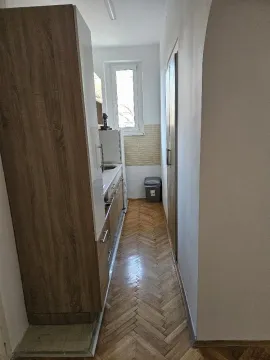 Uska kuhinja sa drvenim elementima i parketom na podu. - image 13