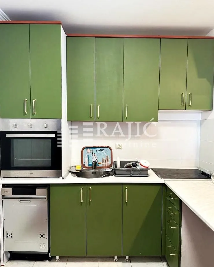 Small kitchen with green cabinets and built-in oven.