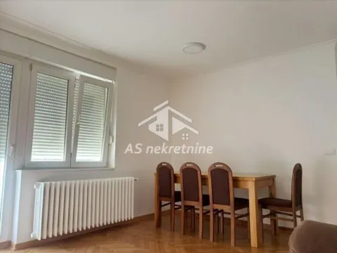 Dining area with a wooden table and chairs in a bright room with windows. - image 5