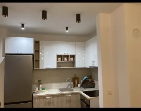Compact kitchen with white cabinets, refrigerator, and built-in stovetop. - image 4