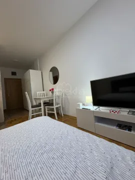 Furnished bedroom with a bed, TV, and a small dining table. - image 2