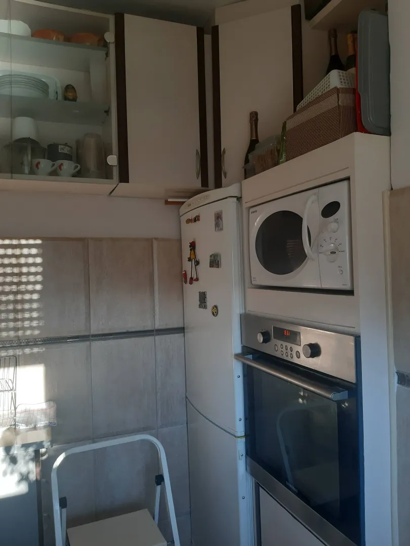 Manja kuhinja sa ugradnim elementima, frižiderom i aparatima.