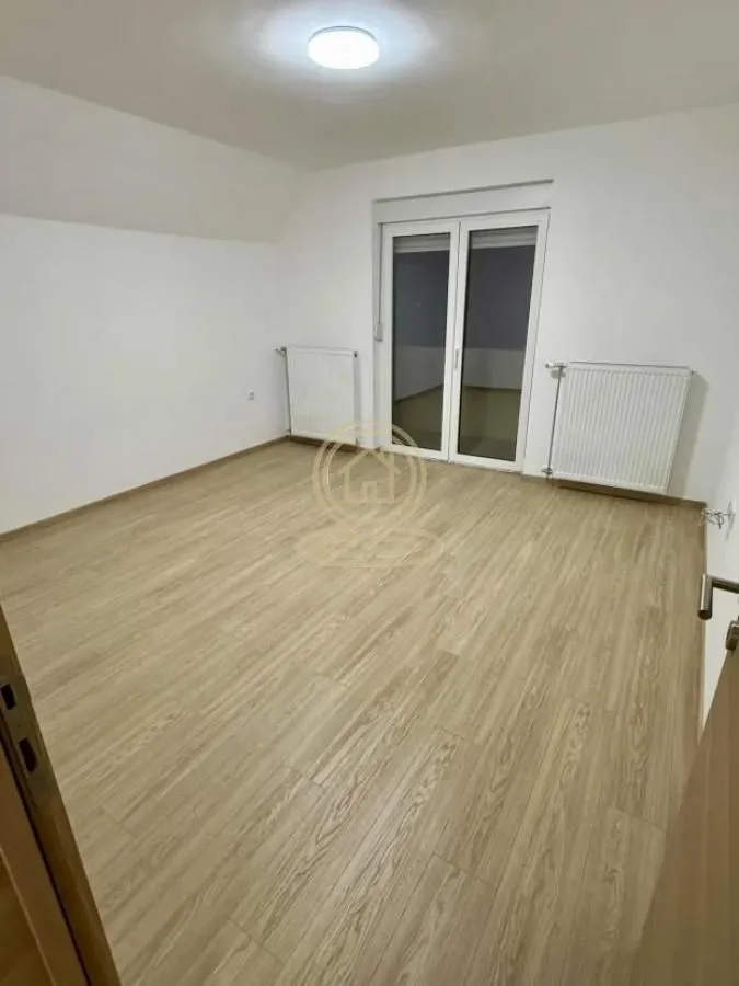 Prazna soba sa laminatom i izlazom na terasu.