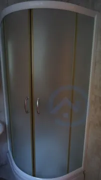 A semi-circular shower cabin with frosted glass doors in a bathroom. - image 11