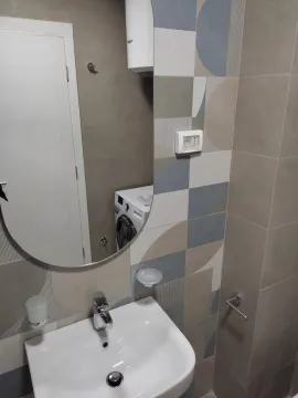Savremeno opremljeno kupatilo sa umivaonikom, ogledalom i mašinom za veš. - image 6