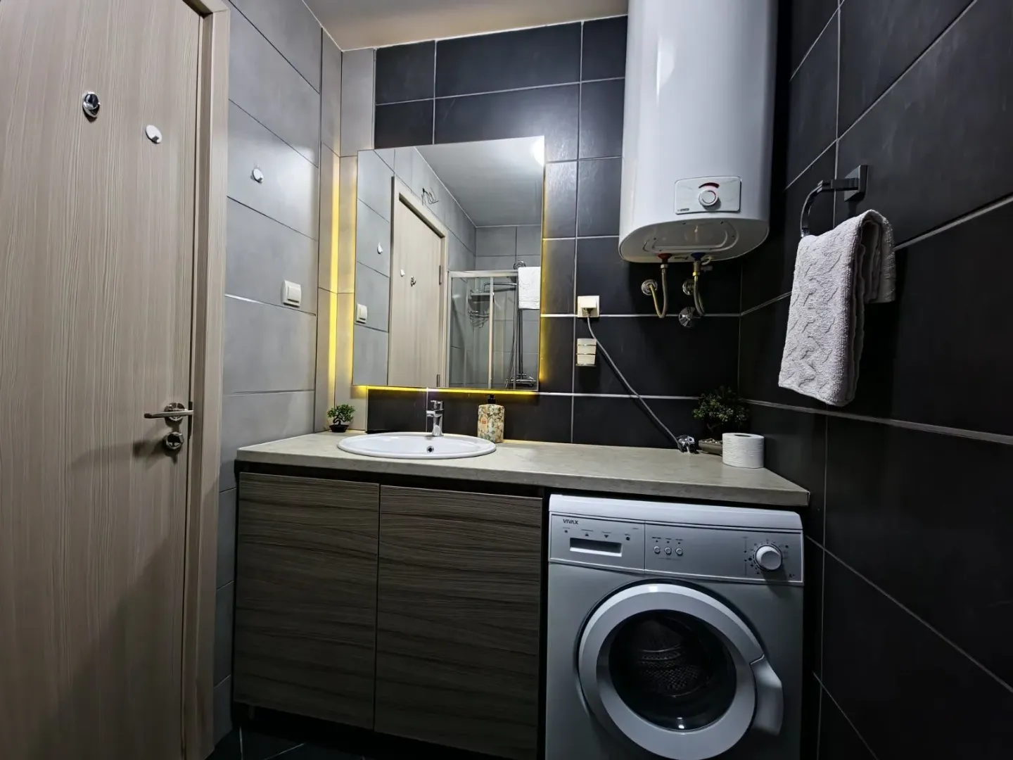 Modern bathroom with a sink, mirror, and washing machine.